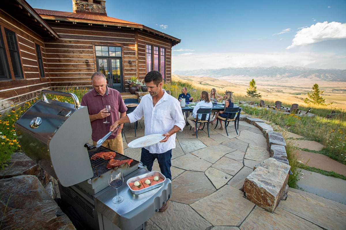 family grilling and sitting on natural stone patio