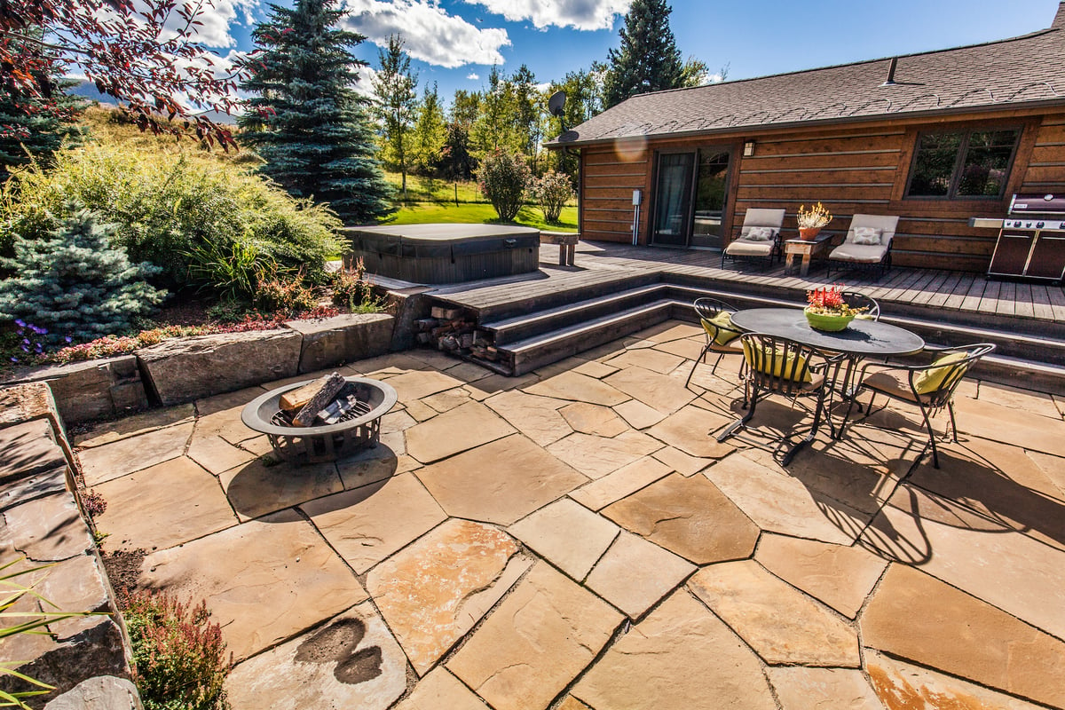 natural stone patio with seating area and hot tub