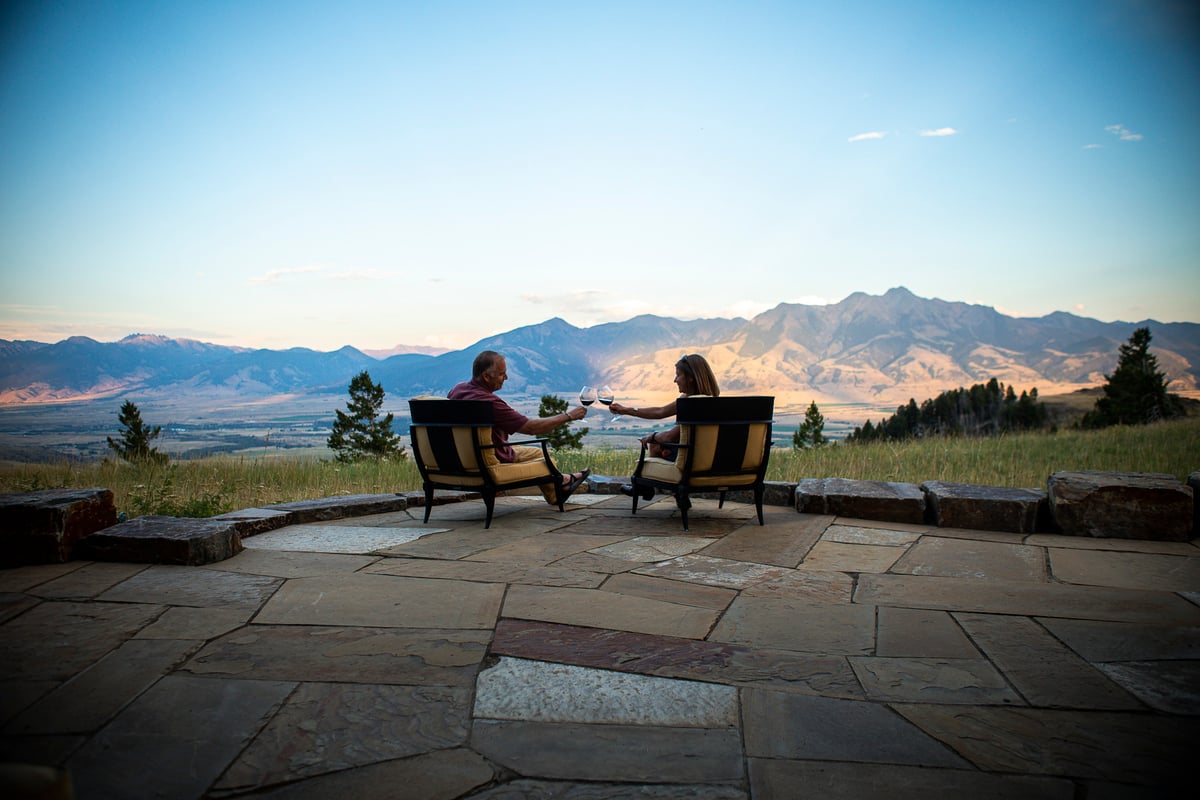 couple sits on natural stone patio with view of mountains