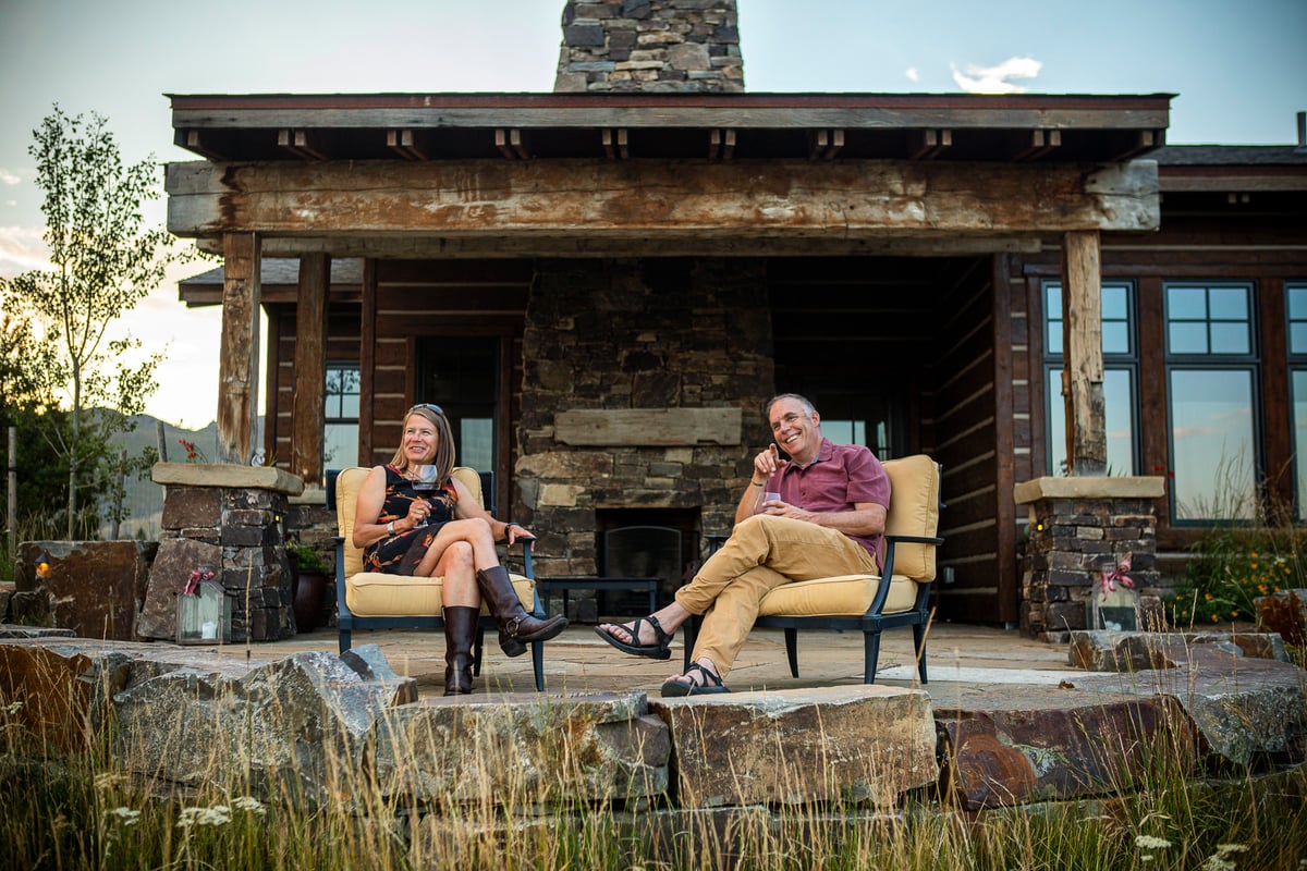 couple sips wine on patio with fireplace