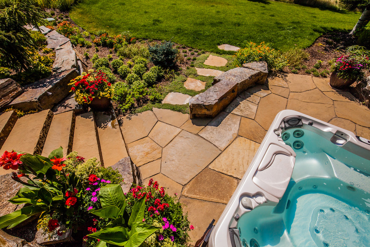natural stone patio and stairs with flowers near hot tub