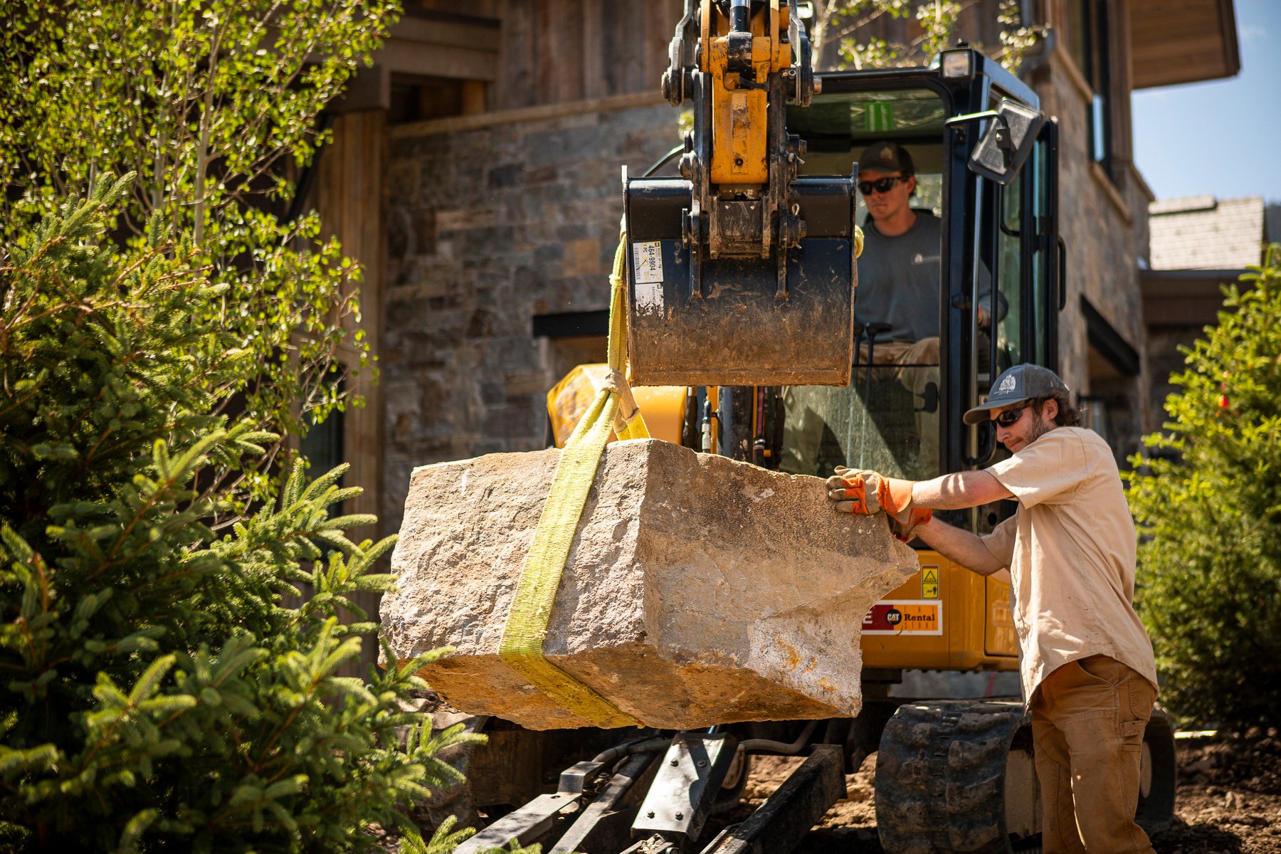 Blanchford team using a backhoe to move a large rock