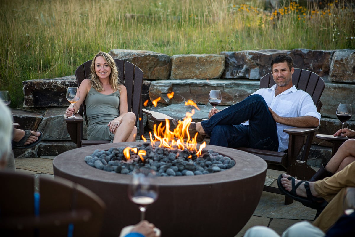 patio with family sitting around fire pit drinking wine 