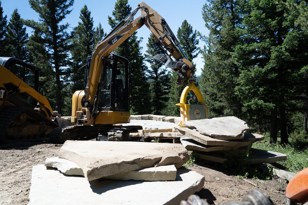 excavator picks up stone for natural patio