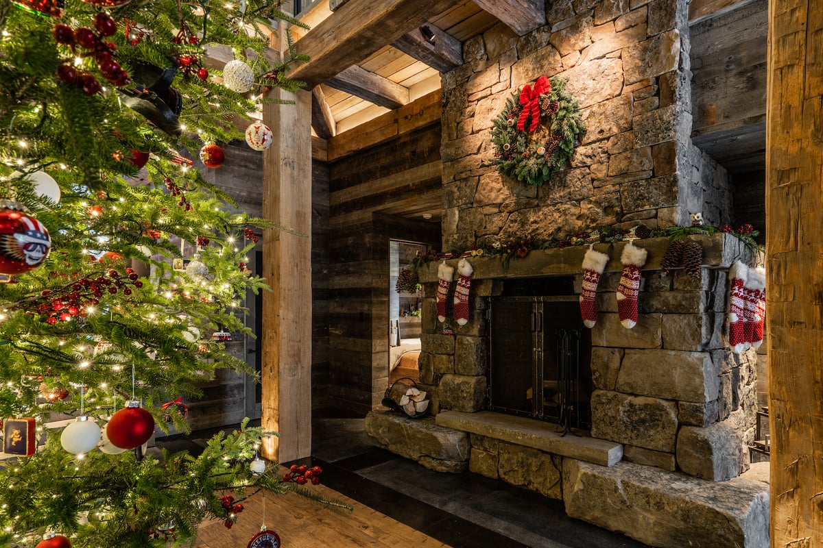 christmas tree with holiday lights and wreath with stockings over fireplace