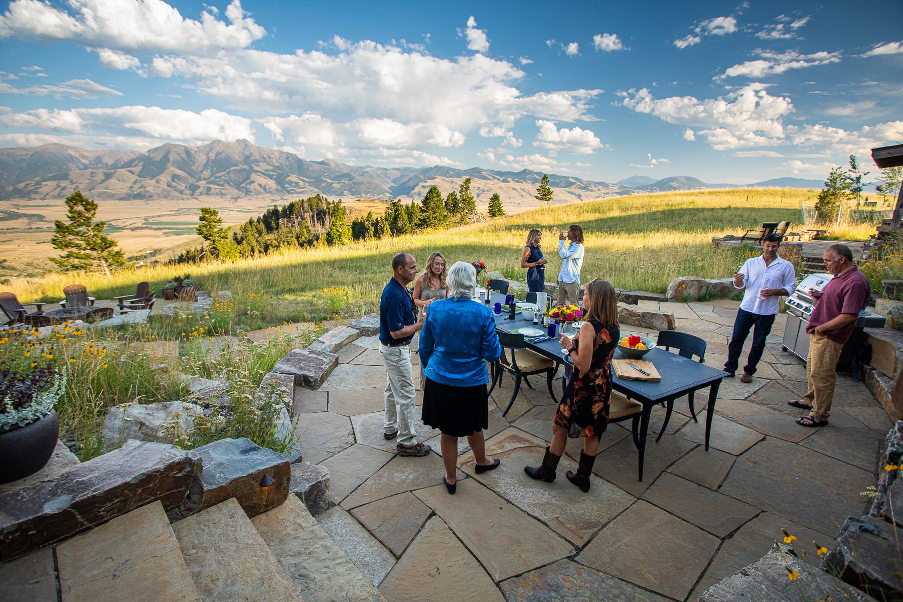 family gathers on patio surrounded by native plantings and mountains