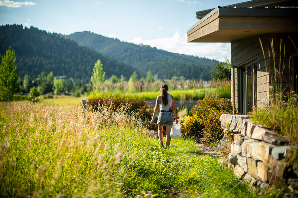 landscape maintenance team carries bucket to weed at property with mountains in background