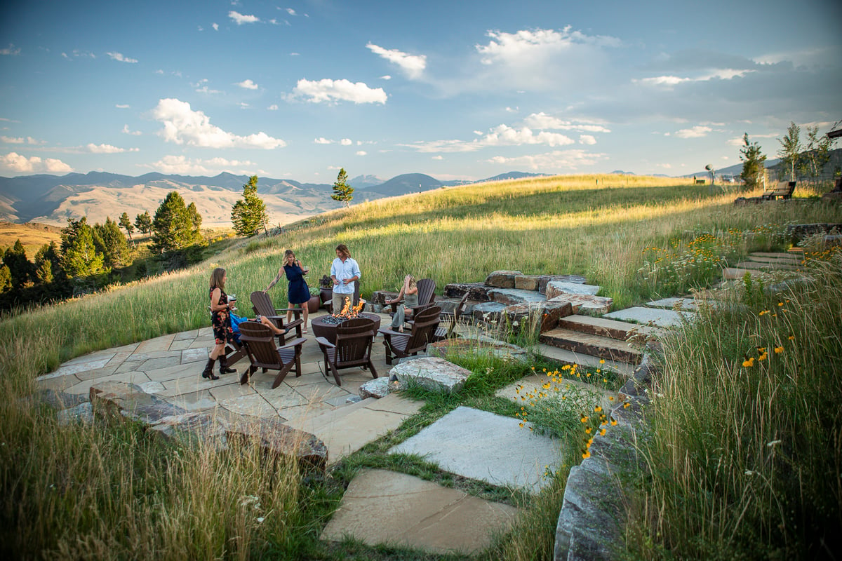 family gathers around walkway and flagstone patio with firepit 